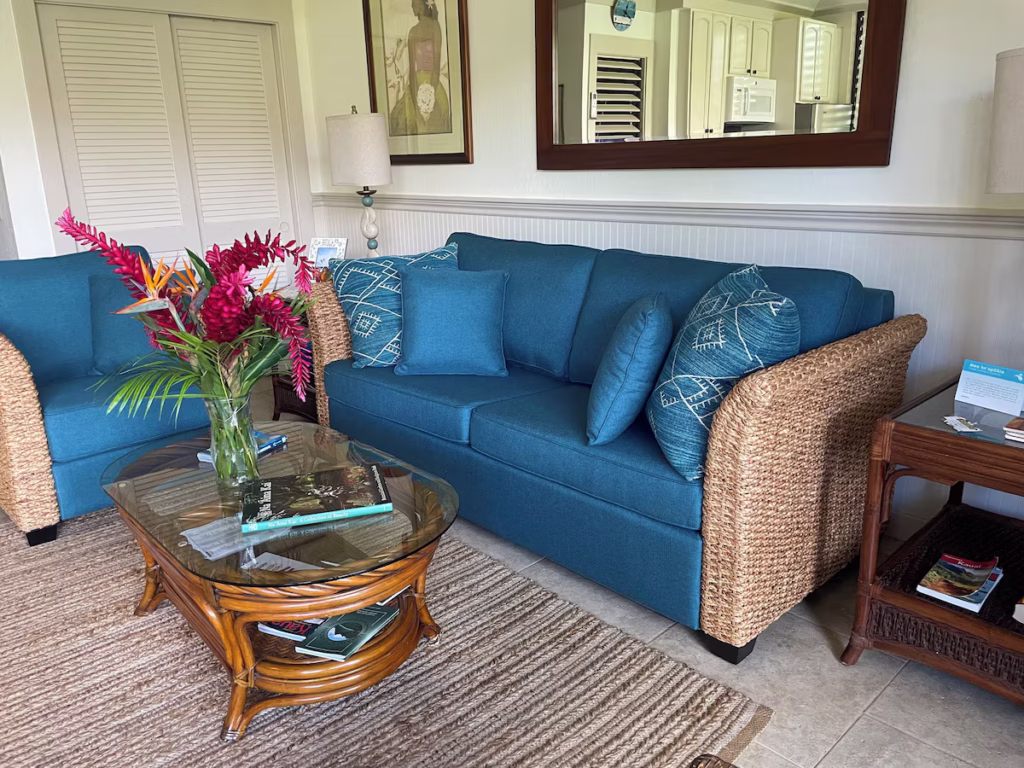 Living area with blue pull out couch and chair with wicker arms and a coffee table.