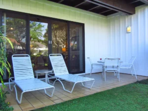 Lanai with two lounge chairs to the left and a table with four seats to the right.