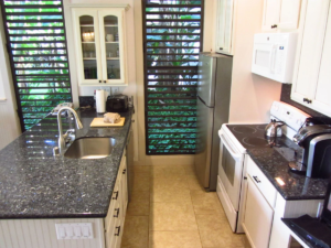 Kitchen view from high with sink peninsula on left and microwave and stove with refridgerator on right.