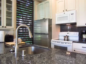 Kitchen sink penninsula in foreground with stove and refrigerator in background.