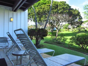 Lanai in the foreground on the left with a view of the lush Kiahuna Plantation gardens in the background on the right.